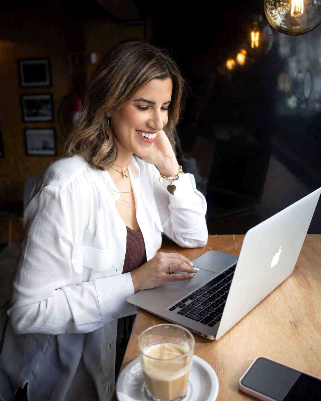 Veronica smiling at her laptop in a café